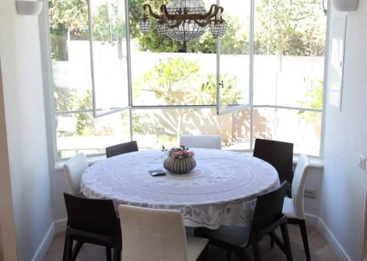 שולחן אוכל עם חלונות בלגיים בחדר אוכל, עם כיסאות בצבעים שונים.